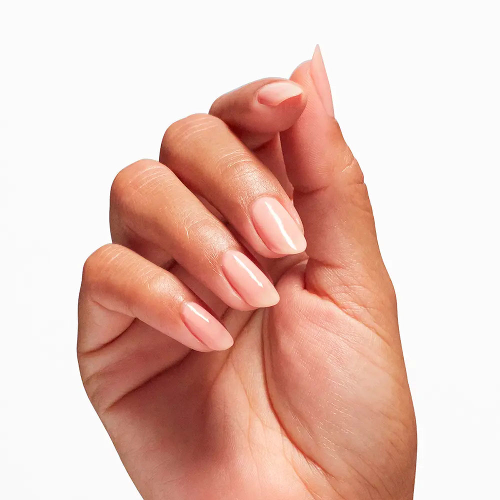 Close-up of a hand with pale pink glossy manicured nails against a white background