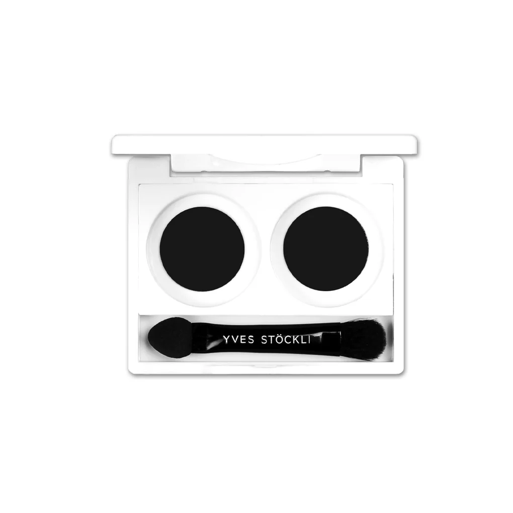 White makeup palette with two black eyeshadows and a small brush labeled 'YVES STÖCKLI'.