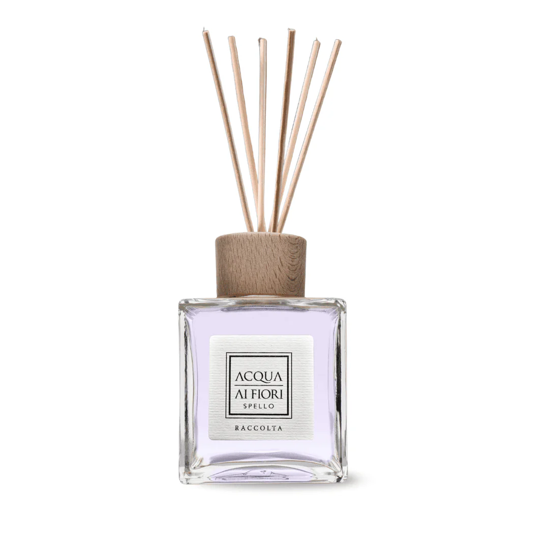 Glass square perfume diffuser with lavender liquid, wooden cap, and several reed sticks extending upward