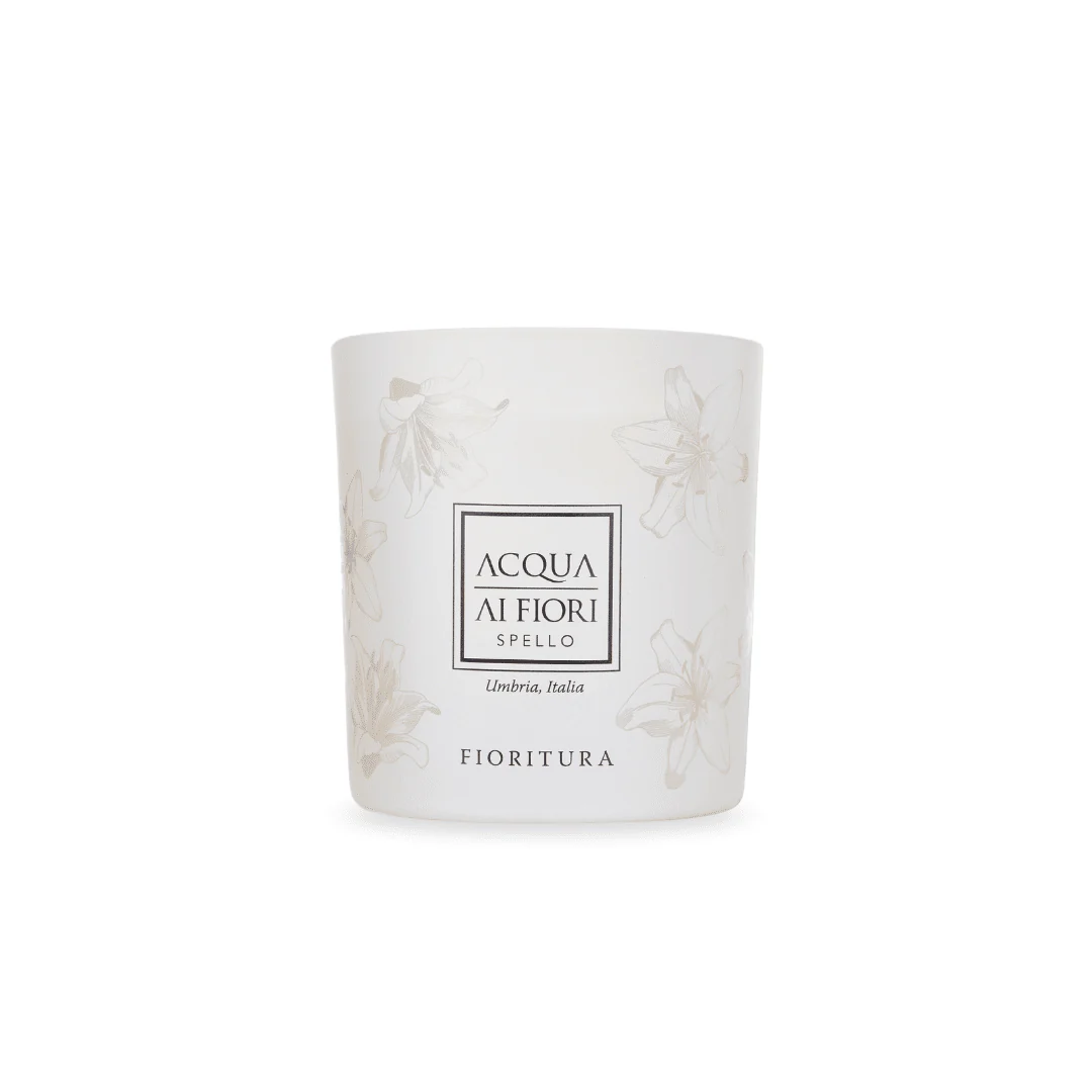 White ceramic candle jar with delicate floral print and a centered label reading 'ACQUA AI FIORI' and 'Fioritura' underneath (Umbria, Italia).
