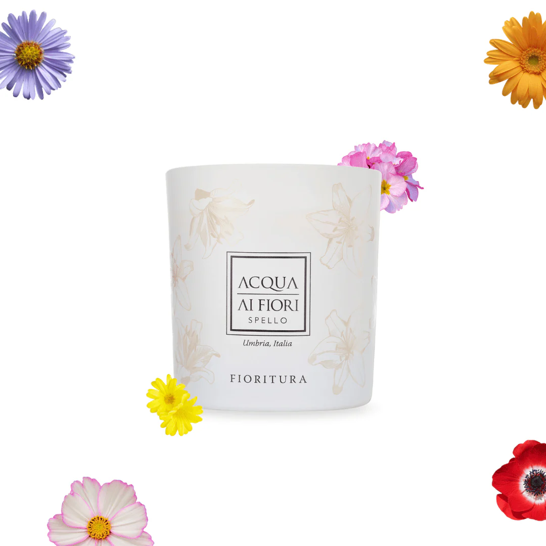 White ceramic container with a subtle floral pattern and the Acqua di Fiori Spello Fioritura logo, surrounded by colorful flowers.