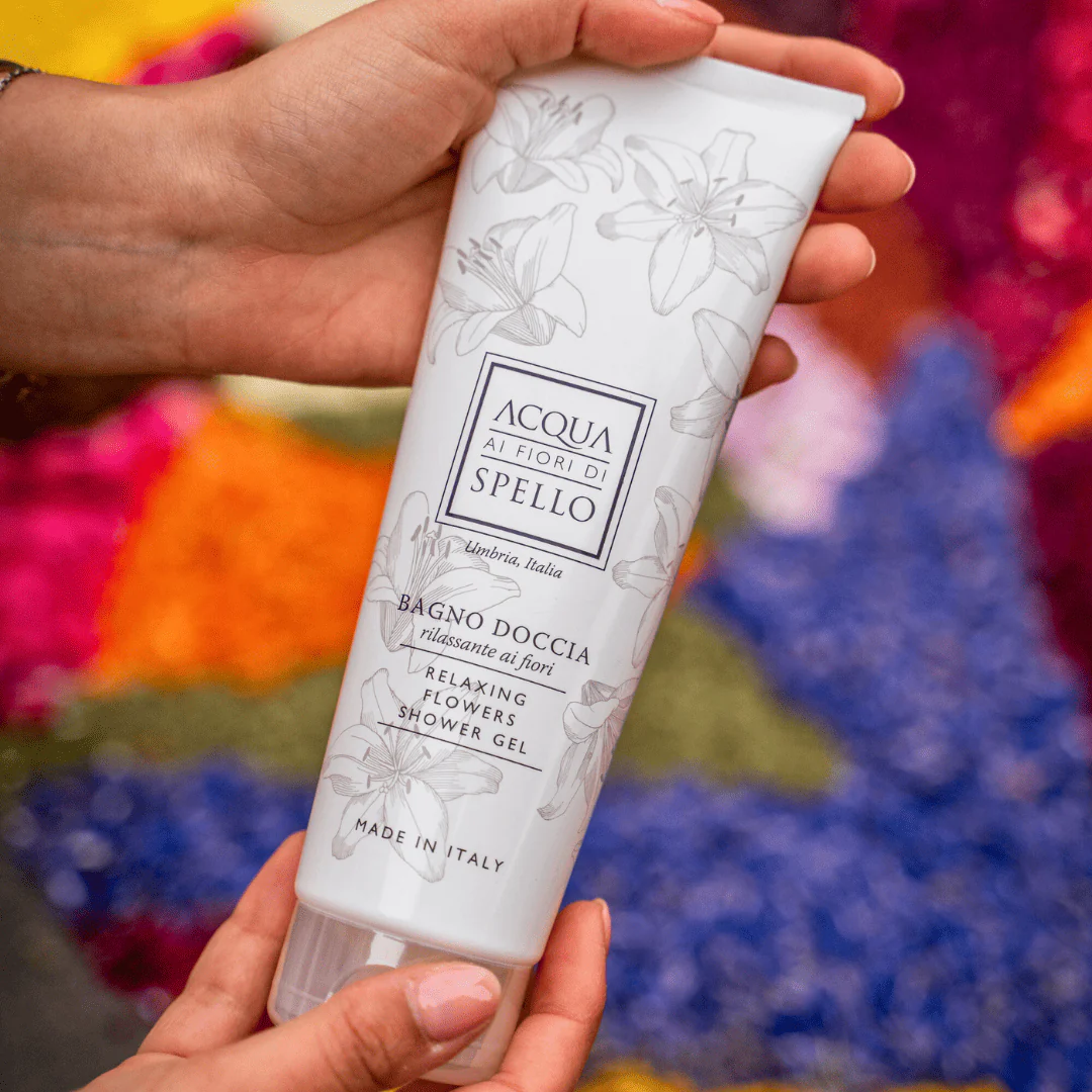 Hands holding a white tube of Acqua Ai Fiori di Spello Relaxing Flowers Shower Gel with floral line art