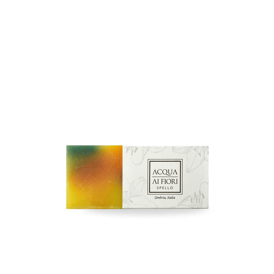 Colorful bar of soap with green-to-orange gradient on the left and a white patterned label on the right reading 'ACQUA AI FIORI' (Italy)