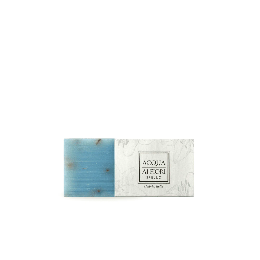 Blue rectangular soap bar beside a white packaging box with a black bordered label reading 'ACQUA LI FIORI' and 'Umbria, Italia'