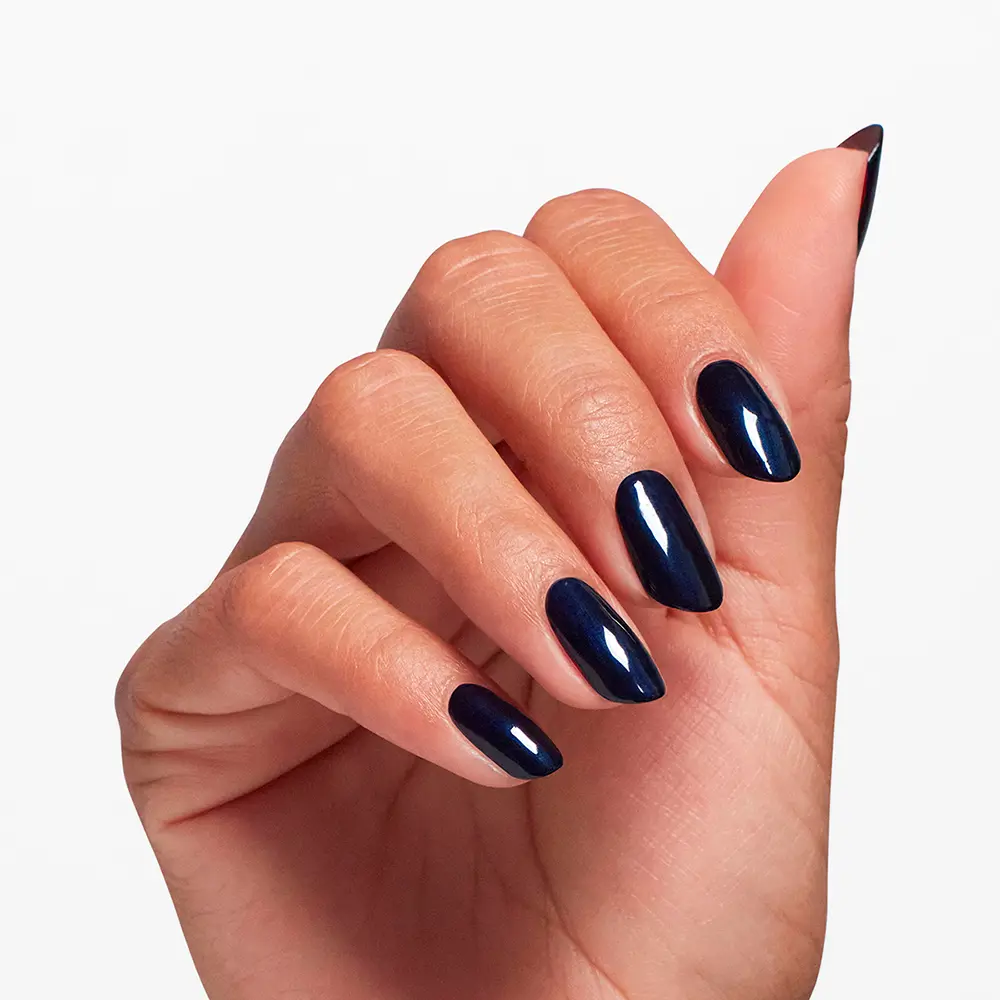 Close-up of a hand displaying glossy navy blue almond-shaped nails against a white background.