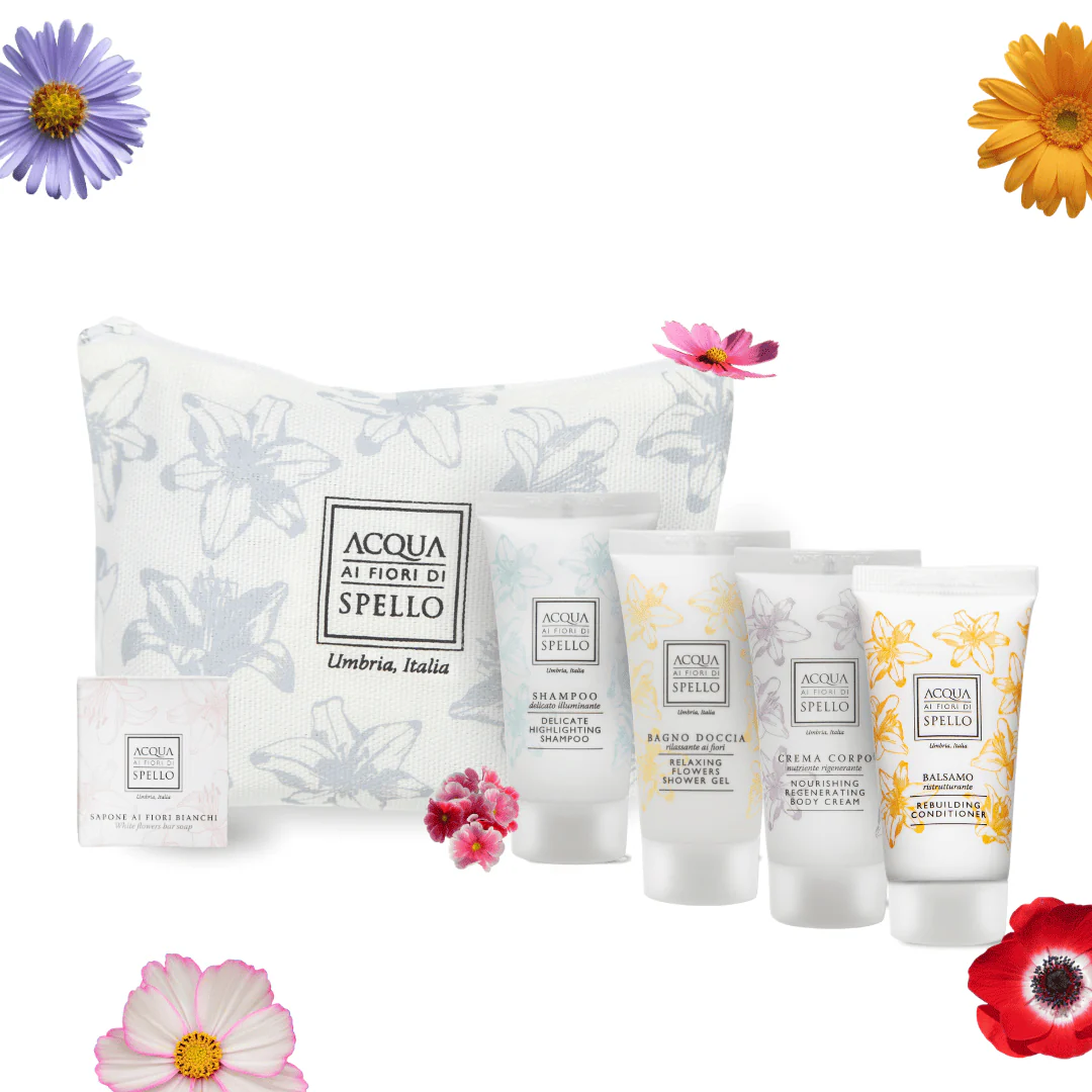 Acqua ai Fiori di Spello skincare gift set with a white floral bag, a small box, and five tubes, surrounded by colorful flowers.