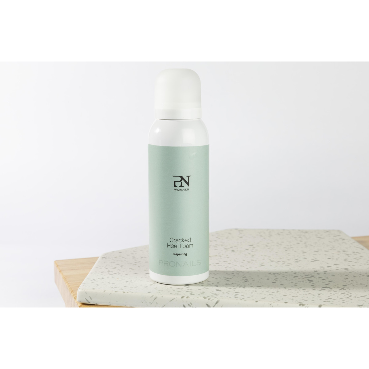 Pronails Cracked Heel Foam bottle standing on a speckled surface.